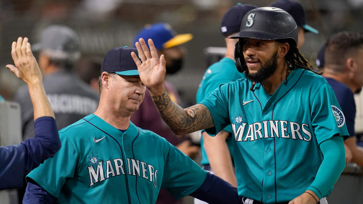 Seattle Mariners’ J.P. Crawford, right, is congratulated by manager Scott Servais, left, and teammates after scoring a run against the Oakland Athletics during the third inning of a baseball game in Oakland, Calif., Monday, Sept. 20, 2021. (AP Photo/Jeff Chiu)