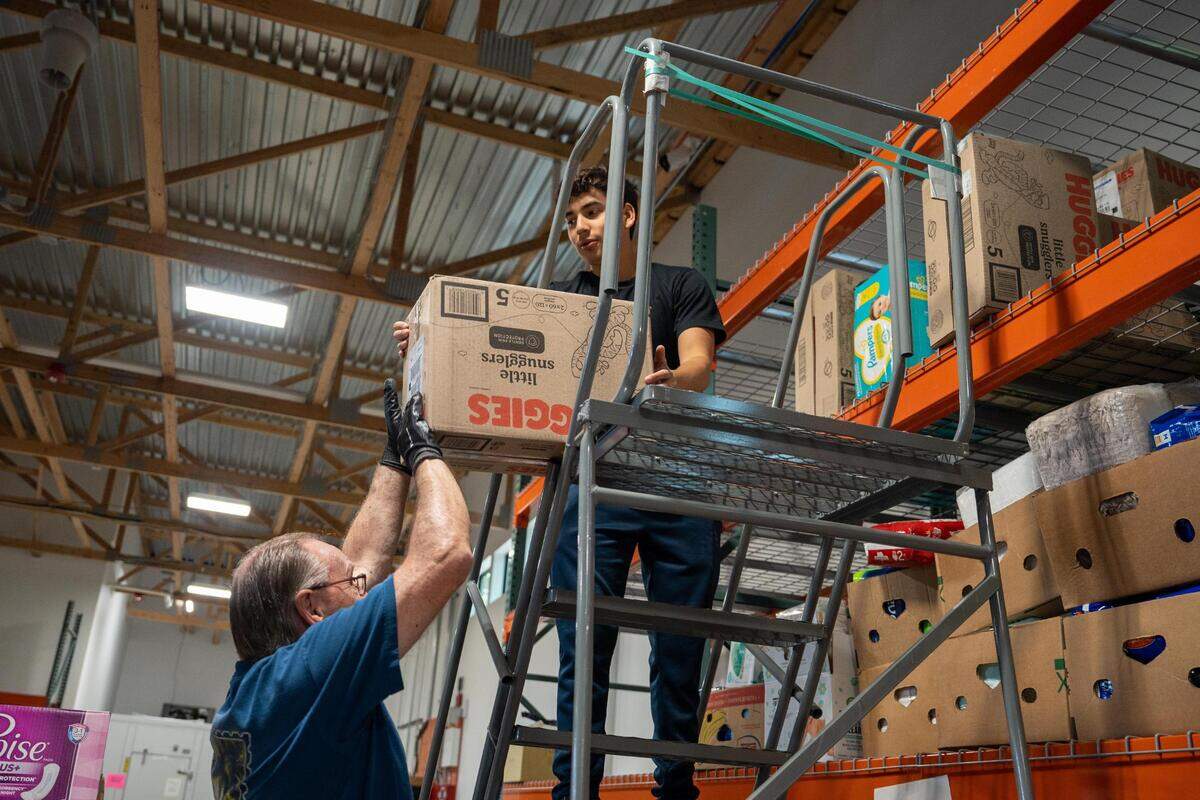 Volunteer Thad Frampton hands Sergio Andrade a box of diapers to stack in the new FISH Food Bank facility in Gig Harbor on Friday July 8, 2022. The new building offers a larger clothing store section, private financial advising rooms, a conference room allowing the board to meet and additional offices for staff.