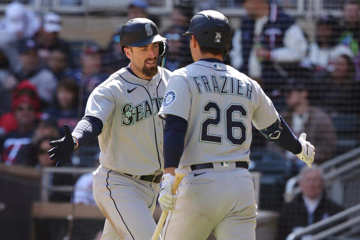 Seattle Mariners catcher Tom Murphy, left, high fives teammate second baseman Adam Frazier (26) after hitting a homer during the fifth inning of a baseball game against the Minnesota Twins, Saturday, April 9, 2022, in Minneapolis. Seattle won 4-3. (AP Photo/Stacy Bengs)