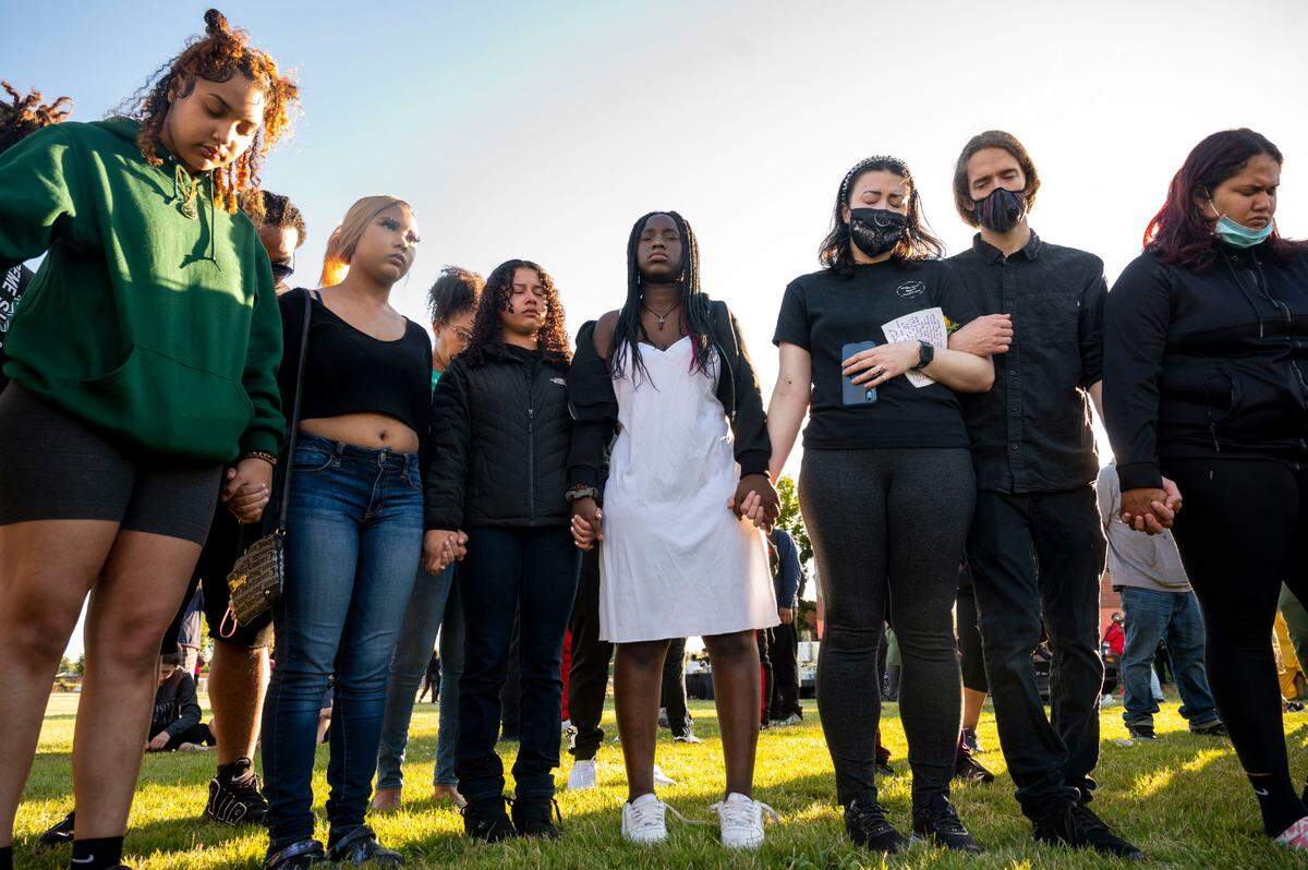 Mourners bow their heads as Bishop Michael Doss leads a prayer during a vigil for Iyana Ussery on Thursday, July 7, 2022, at Stanley Playfields in Tacoma, Wash.