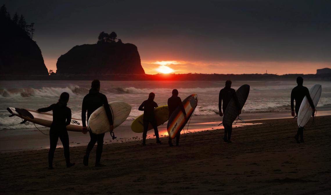 Surfers walk back to campat sunset along First Beach in LaPush, Washington, on Saturday, July 20, 2024.