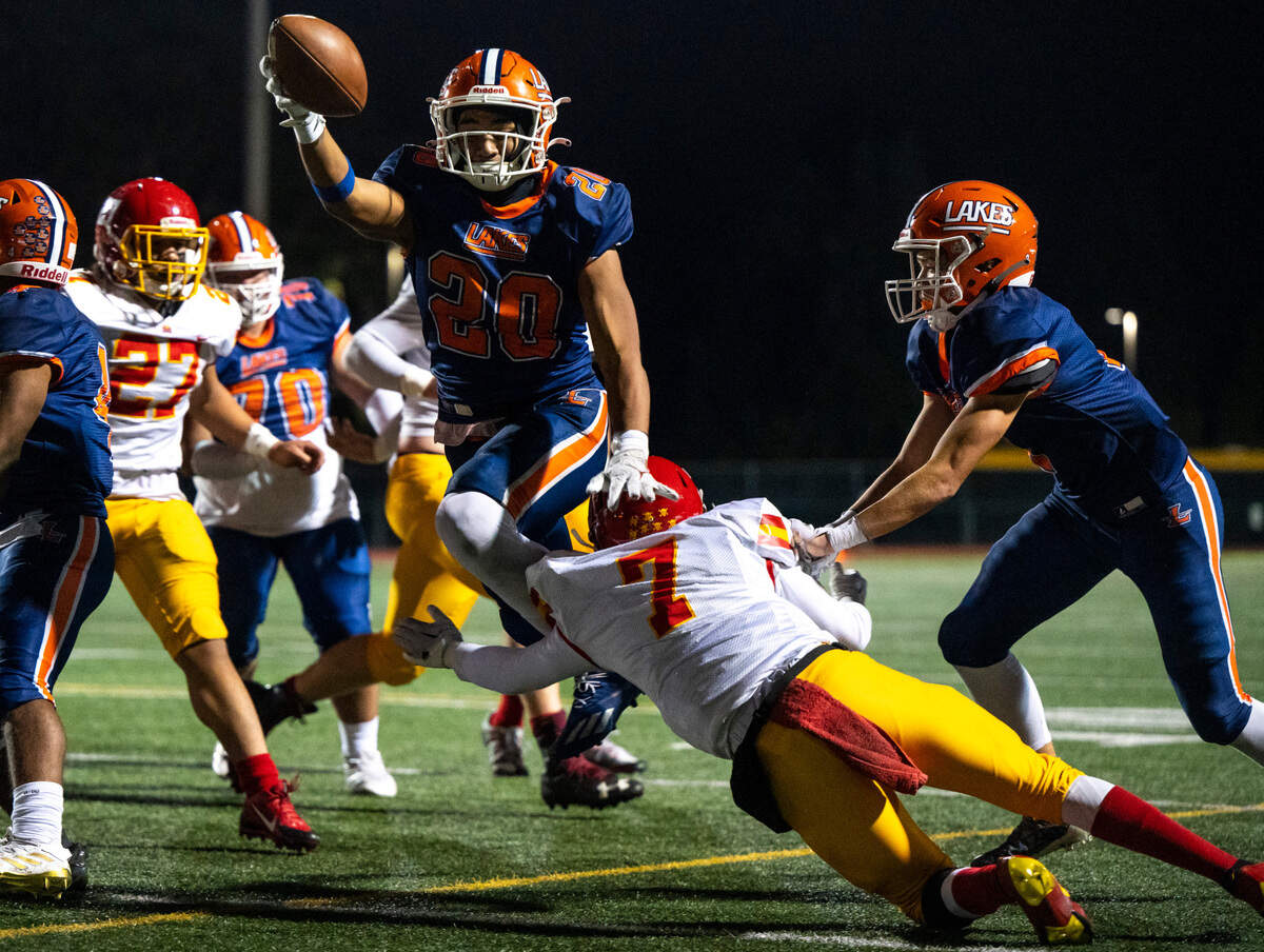 Lakes running back Leo Pulalasi, 20, jumps into the end zone over Mount Tahoma cornerback Quincy Mitchell, 7, and scores a touchdown in the second quarter of a Thursday night game at Harry E. Lang Stadium in Lakewood, Wash. on Oct. 27, 2022. Lakes defeated Mount Tahoma 51-14.