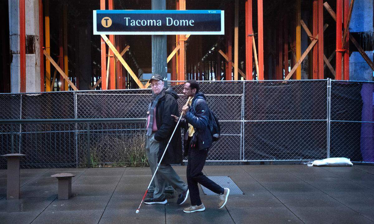 Lucas Smiraldo walks with Tacoma Area Commision on Disabilities chair Amin “Tony” Hester at the Tacoma Light Rail T-Line at the Tacoma Dome Station in Tacoma, Washington, on Thursday, Nov. 9, 2023.