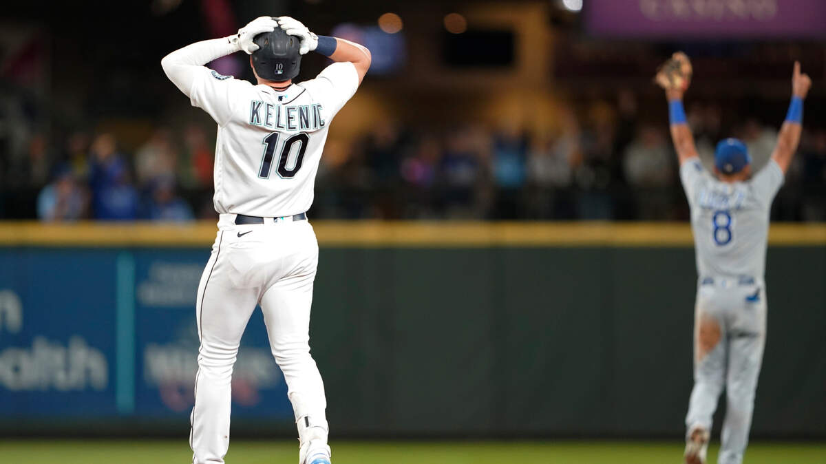 Seattle Mariners’ Jarred Kelenic (10) and Kansas City Royals shortstop Nicky Lopez (8) react after Royals left fielder Andrew Benintendi made a leaping catch at the wall of a ball hit by Kelenic during the eighth inning of a baseball game Thursday, Aug. 26, 2021, in Seattle. (AP Photo/Ted S. Warren)