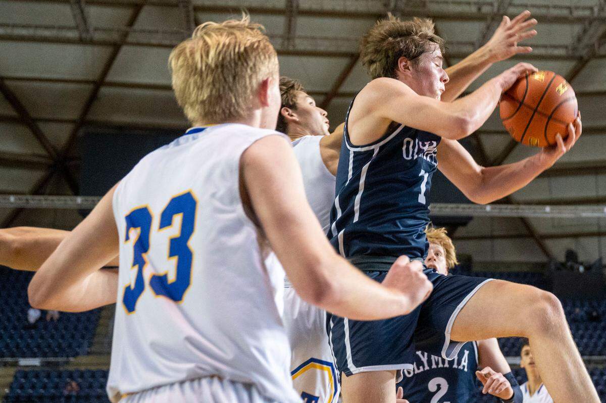 Olympia guard Caden Roth (1) grabs a defensive rebound away from a pair of Tahoma players during the third quarter of a Class 4A quarterfinal state tournament game on Thursday, March 3, 2022, at the Tacoma Dome, in Tacoma, Wash.