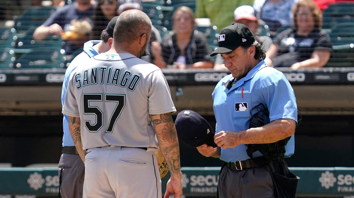 Home Plate umpire Phil Cuzzi, right, checks Seattle Mariners relief pitcher Hector Santiago’s hat during the fifth inning in the first baseball game of a doubleheader against the Chicago White Sox in Chicago, Sunday, June 27, 2021. Seattle Mariners relief pitcher Hector Santiago ejected by Home Plate umpire Phil Cuzzi. (AP Photo/Nam Y. Huh)