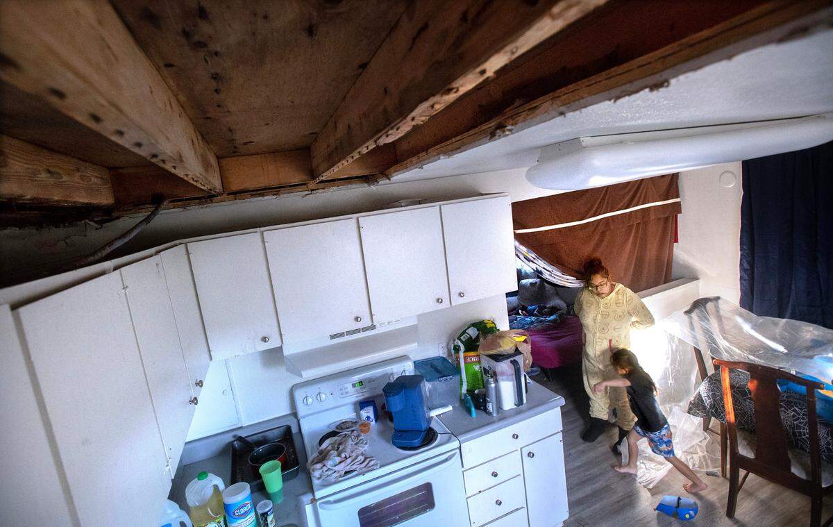 KayleenRose Babauta uses blankets to separate the living room from the kitchen, where she fears the spread of mold spores from the water-damaged open ceiling and walls of the second-floor apartment where she lives with her husband and five children at the Legacy Park Apartments in Lakewood, Washington, on Wednesday, Nov. 8, 2023.