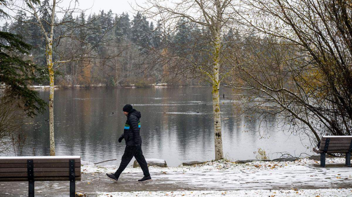 A man walks along a snowy pathway at Wapato Park in Tacoma on Tuesday, Nov. 29, 2022. A body was discovered floating in the lake there Friday.