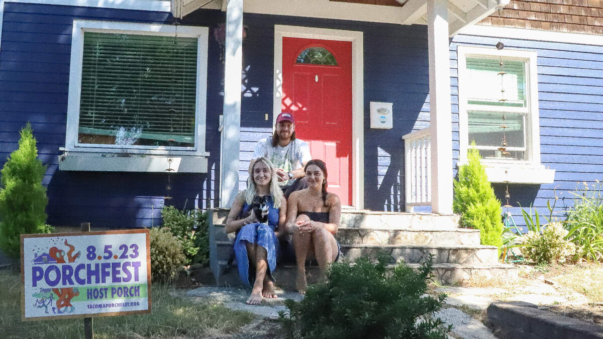 Zophia Heck, bottom left, Max Finley, middle, and Solana Sartain, bottom right, sit in front of their home in Central Tacoma on Wednesday, August 2, 2023. They will host three band performances on their porch, including Finley’s own band.