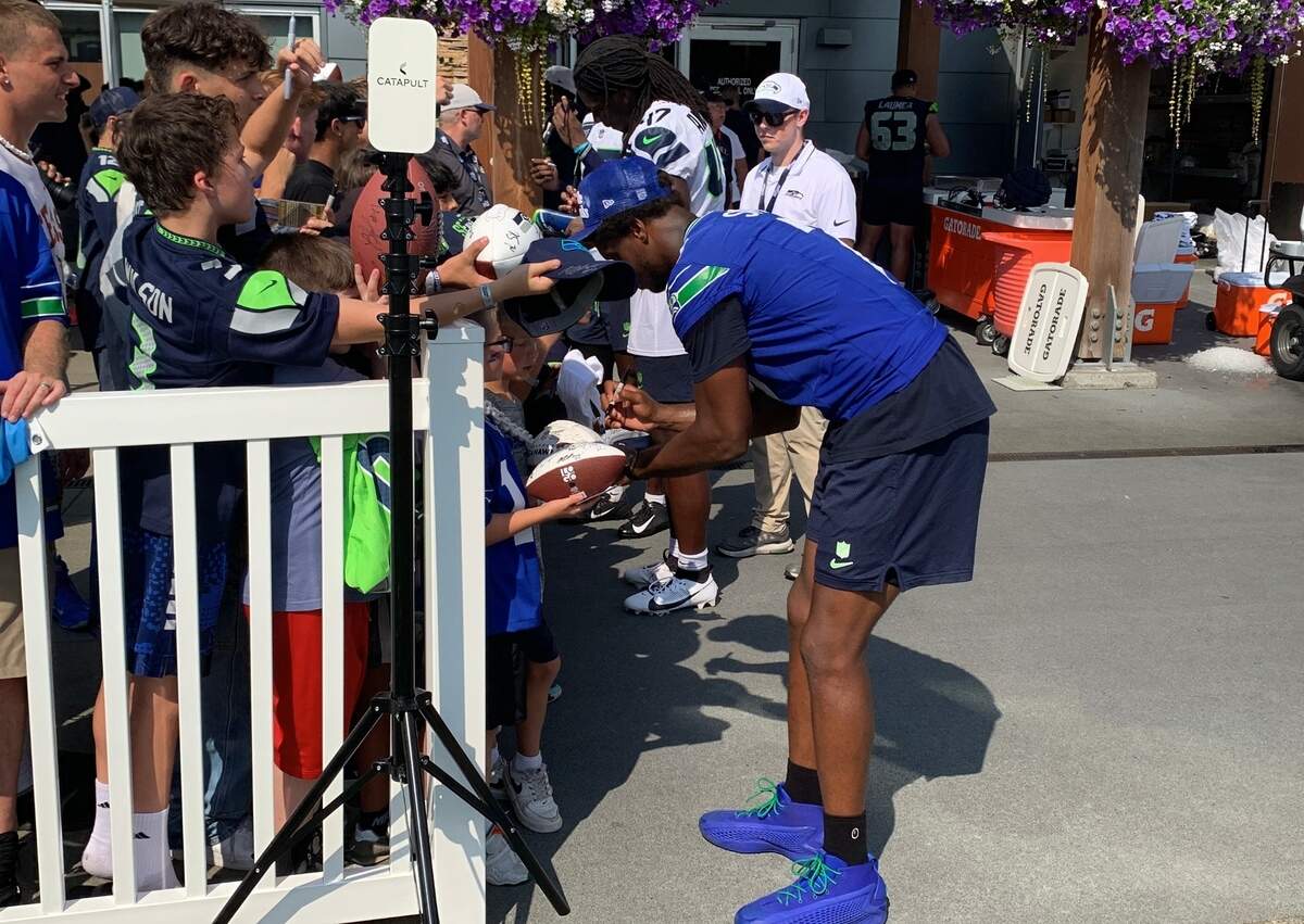 Pro Bowl quarterback Geno Smith gets down to the level of a boy to sign an autograph for him following the ninth practice of Seahawks training camp on Aug. 2, 2024, at the Virginia Mason Athletic Center in Renton. Smith missed practice for the third consecutive day with knee and hip issues the team does not believe is serious.
