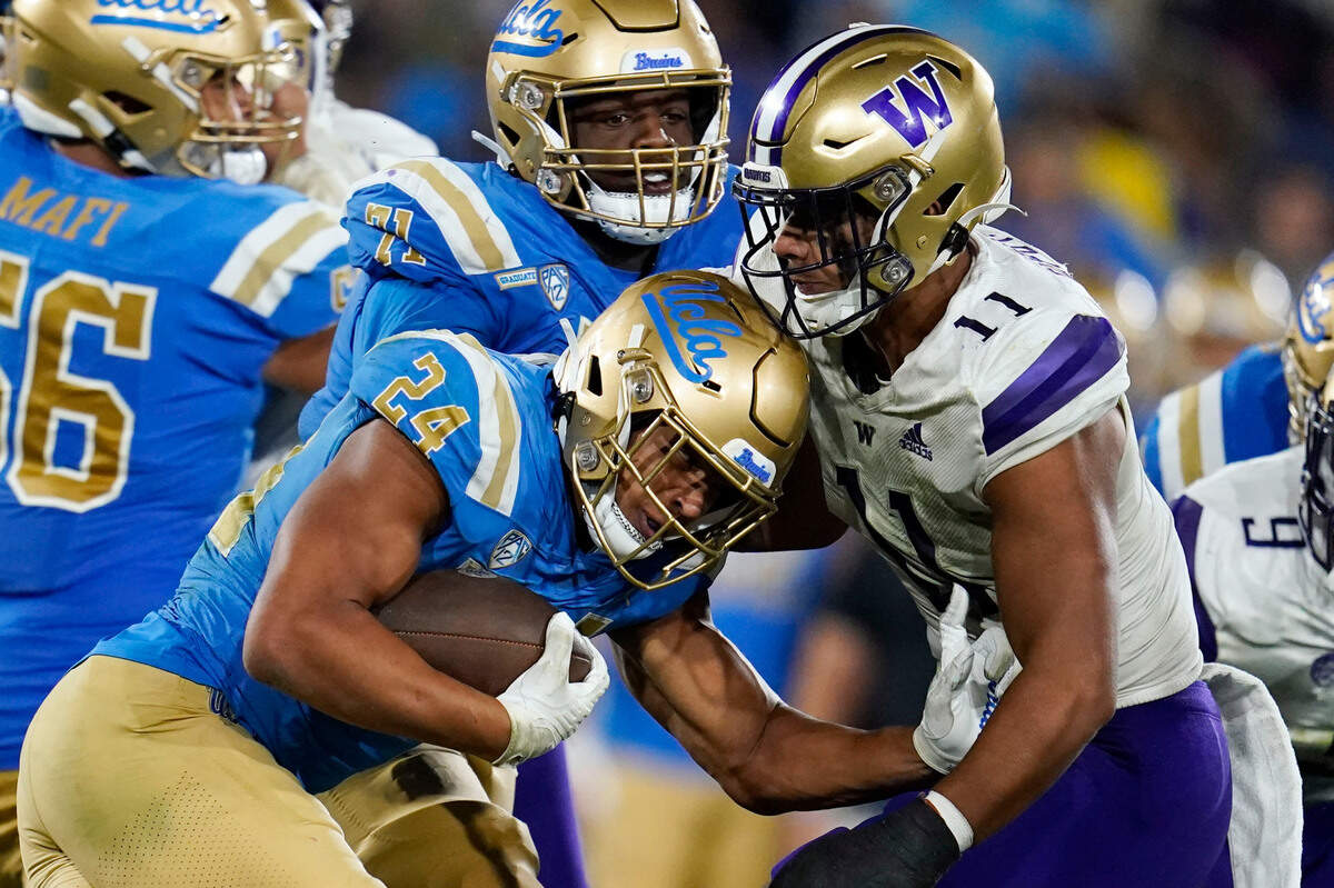 UCLA running back Zach Charbonnet (24) is tackled by Washington linebacker Alphonzo Tuputala (11) during the second half of an NCAA college football game Friday, Sept. 30, 2022, in Pasadena, Calif. (AP Photo/Marcio Jose Sanchez)