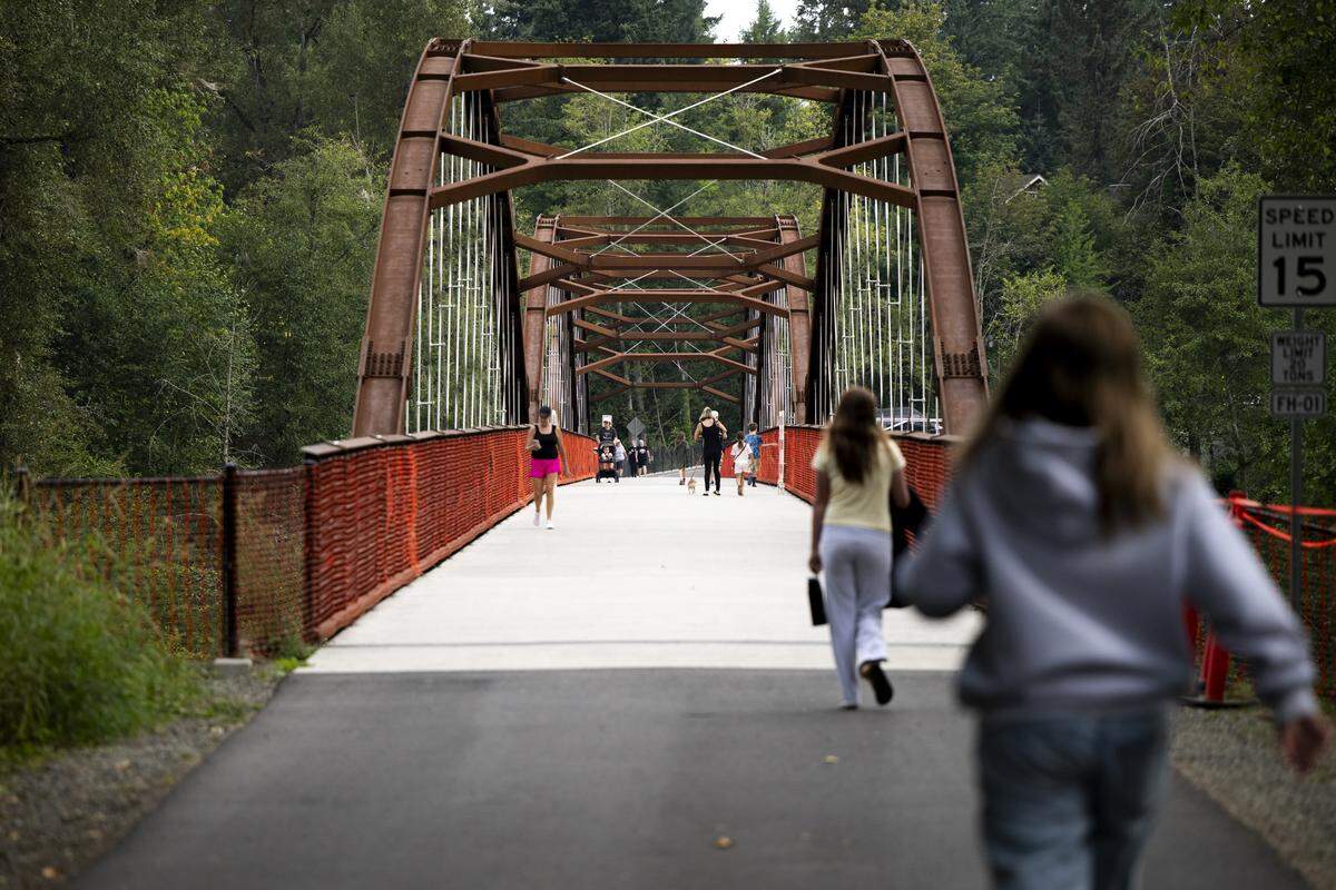 People walk and ride across the Foothills Trail Bridge as the White River Bridge remains closed on Wednesday, Aug. 27, 2025, in Buckley. The Foothill Bridge over the White River is the only thing connecting the towns of Buckley and Enumclaw.