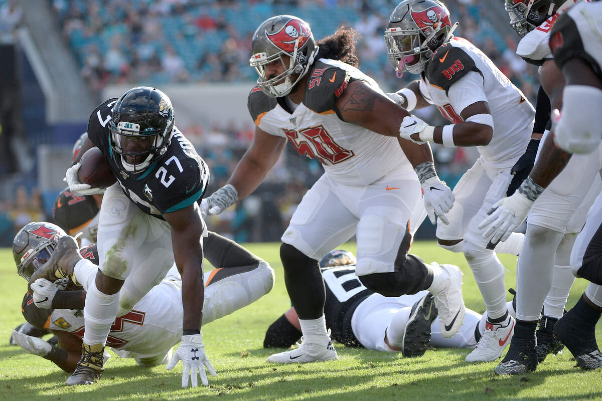Jacksonville Jaguars running back Leonard Fournette (27) rushes for yardage in front of Tampa Bay Buccaneers outside linebacker Lavonte David (54), left, and defensive tackle Vita Vea (50) during the second half of an NFL football game Sunday, Dec. 1, 2019, in Jacksonville, Fla. (AP Photo/Phelan M. Ebenhack)