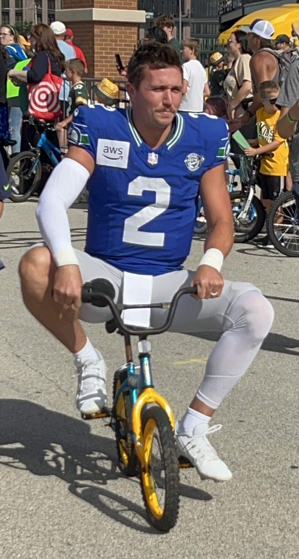Quarterback Drew Lock, 6 feet 4, rides a Green Bay kid’s way-too-small-for-him bike from the Seahawks’ locker room at Lambeau Field down a road to the field Seattle had an NFL preseason joint practice with the Packers in Wisconsin Thursday, Aug. 21, 2025.