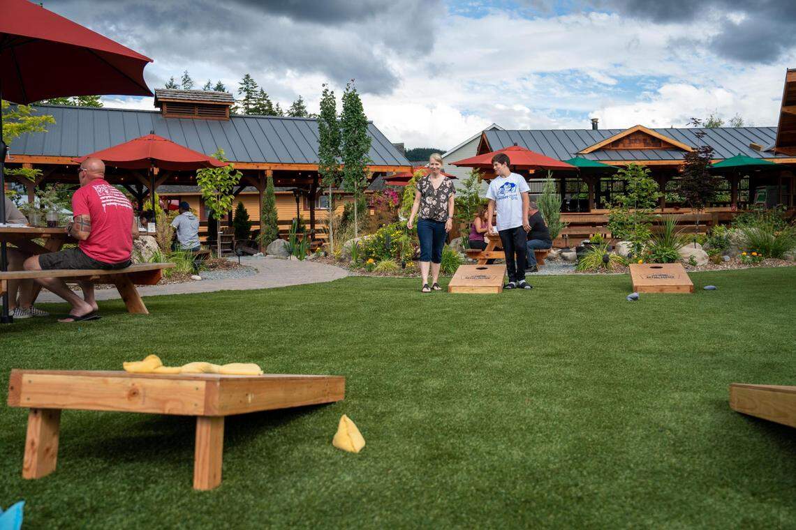 Donna Ragazzo and her son Jarin play cornhole on the lawn at Mill Haus on Thursday July 7, 2022. Locals and visitors alike flock here for cider, snacks and live music on an outdoor stage.