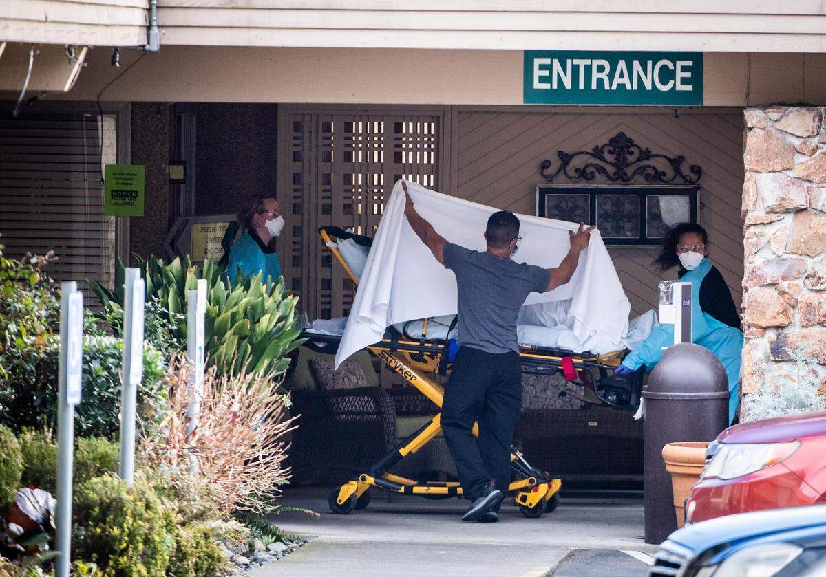A person is brought out on a gurney to an ambulance at the LifeCare Center in Kirkland on Saturday..