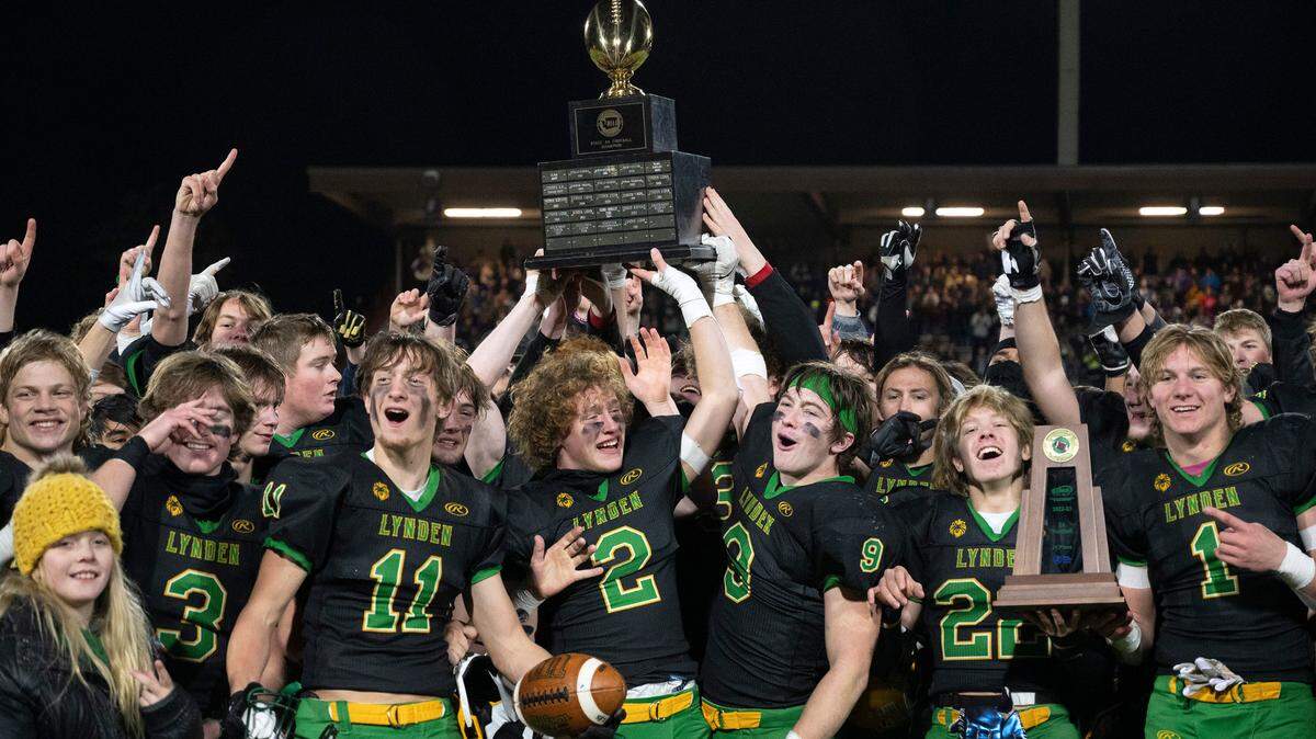 Lynden players celebrate with their state championship trophy following the Lions’ 31-24 victory over the North Kitsap Vikings during the 2A football state championship game at Sparks Stadium in Puyallup, Washington, on Saturday, Dec. 3.
