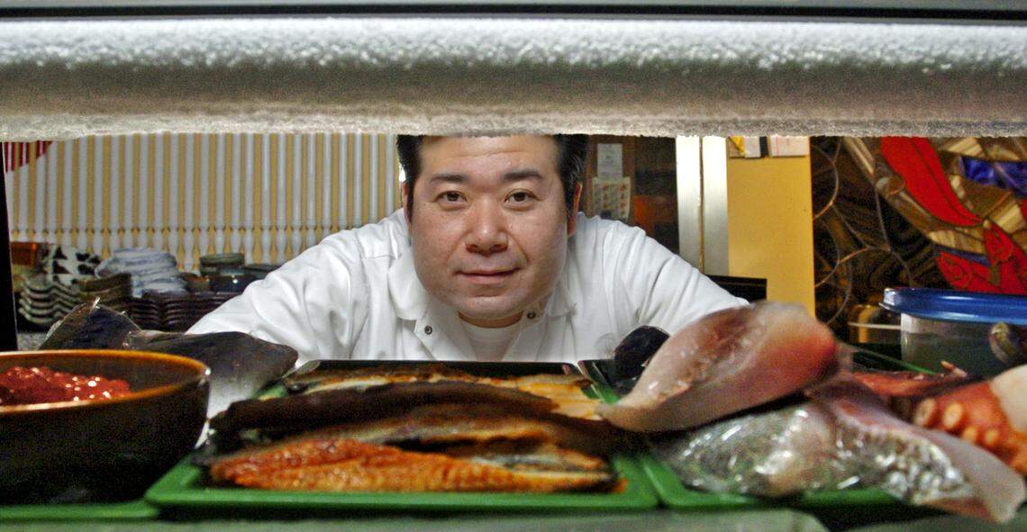 Kazuya "Kazu" Kamada owner and chef of Gari of Sushi on So. 38th in Tacoma.  He is looking through the chilled case with fish and other sushi ingredients.