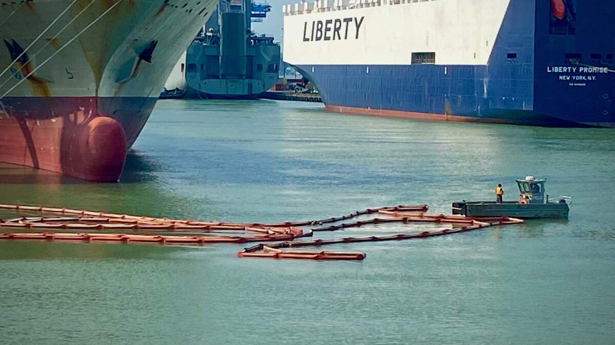 A crew tends to a boom in the Sitcum Waterway at the Port of Tacoma Wednesday afternoon. Sediment-filled water from the Puyallup River is turning Commencement Bay various shades of white, green and blue.