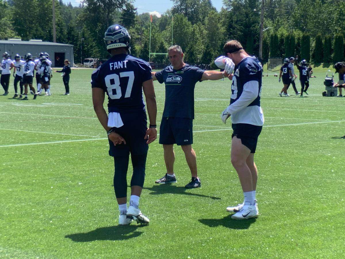 Noah Fant (87) and Will Dissly (right, wiping brow) listen to tight ends coach Pat McPherson instruct during Seahawks offseason organized team activities (OTAs) May 31, 2022, at team headquarters in Renton.