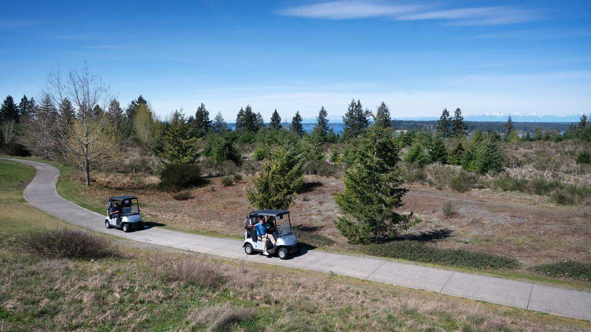 Golfers on The Home Course golf course roll past the undeveloped land planned for housing, commercial property and open spaces in DuPont, Washington, on Tuesday, April 3, 2024.