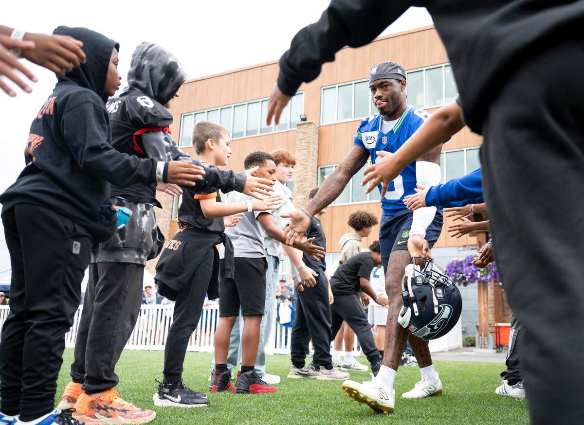Seattle Seahawks quarterback Jalen Milroe (6) high-fives fans during training camp at Virginia Mason Athletic Center on Friday, July 25, 2025, in Renton, Wash.
