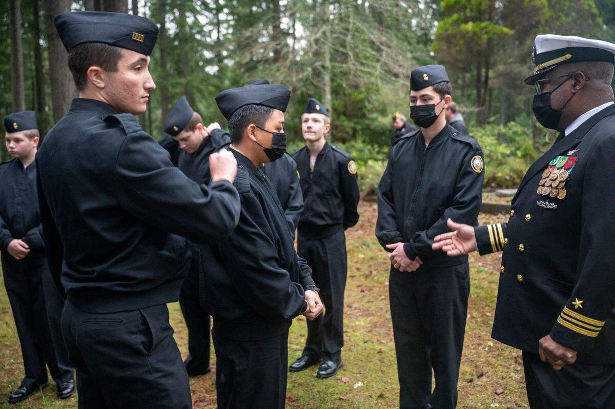 Lieutenant Commander Darrell Hood looks on as cadets in the Peninsula Navy National Defense Cadet Corps get their uniforms adjusted prior to participating at a Wreaths Across America at Artondale Cemetery in Gig Harbor, Wash., on Saturday, Dec. 18, 2021.
