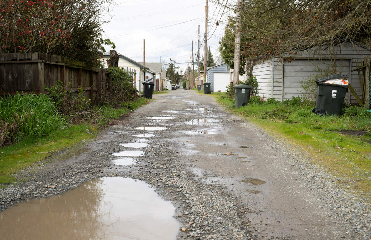 Evan Aeschlimann stands in the alley behind his home, him and his wife were informed it’s part of a Local Improvement District and they’d have to pay $16K for a project to pave it, on Monday, March 31, 2025, in Tacoma, Wash.