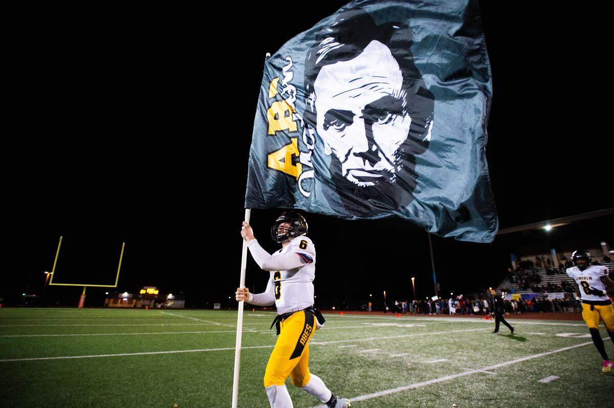 Lincoln’s Caden Filer waves the Abes flag after the game. Lincoln played Lakes in a football game at Harry Lang Stadium in Lakewood, Wash., on Friday, Oct. 25, 2019.