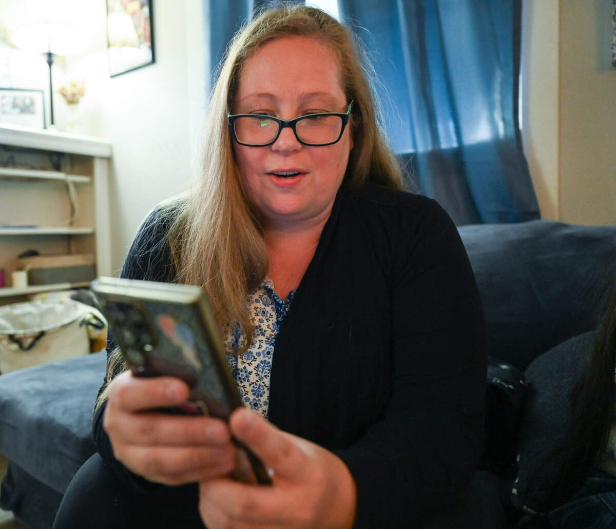 Mackenzie Kuhnle goes through photos of items that her cat Oakley has brought home on Aug. 20 in her home in Puyallup. Oakley has become a local celebrity on the Facebook community page Being Neighborly: Puyallup for his habit of stealing shoes and other items from neighbors. Kuhnle posts in the group to try to return items that Oakley has brought home.