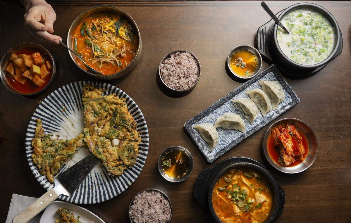 A feast at Yi’s in Lakewood can include the ox-bone broth in several forms, paired with other Korean staples. On the left: radish kimchi, hangover soup and pajeon. On the right: sseolleongtang, dumplings, cabbage kimchi and soft tofu soup.
