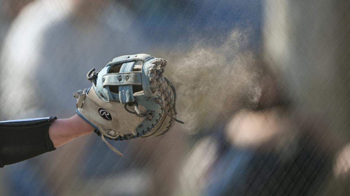 Dust flies as Puyallup’s Kylie Landberg (12) catches a strike against Emerald Ridge during the softball game at Puyallup High School, on Friday, April 18, 2025, in Puyallup, Wash.