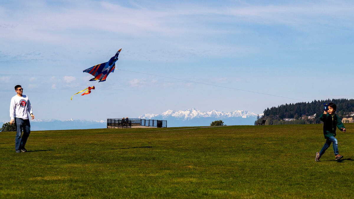 William Sanborn, of DuPont, watches as his son, Desmond, 5, flies a kite in the park at Chambers Creek Regional Park on a Wednesday, April 7, 2022, in University Place, Wash.