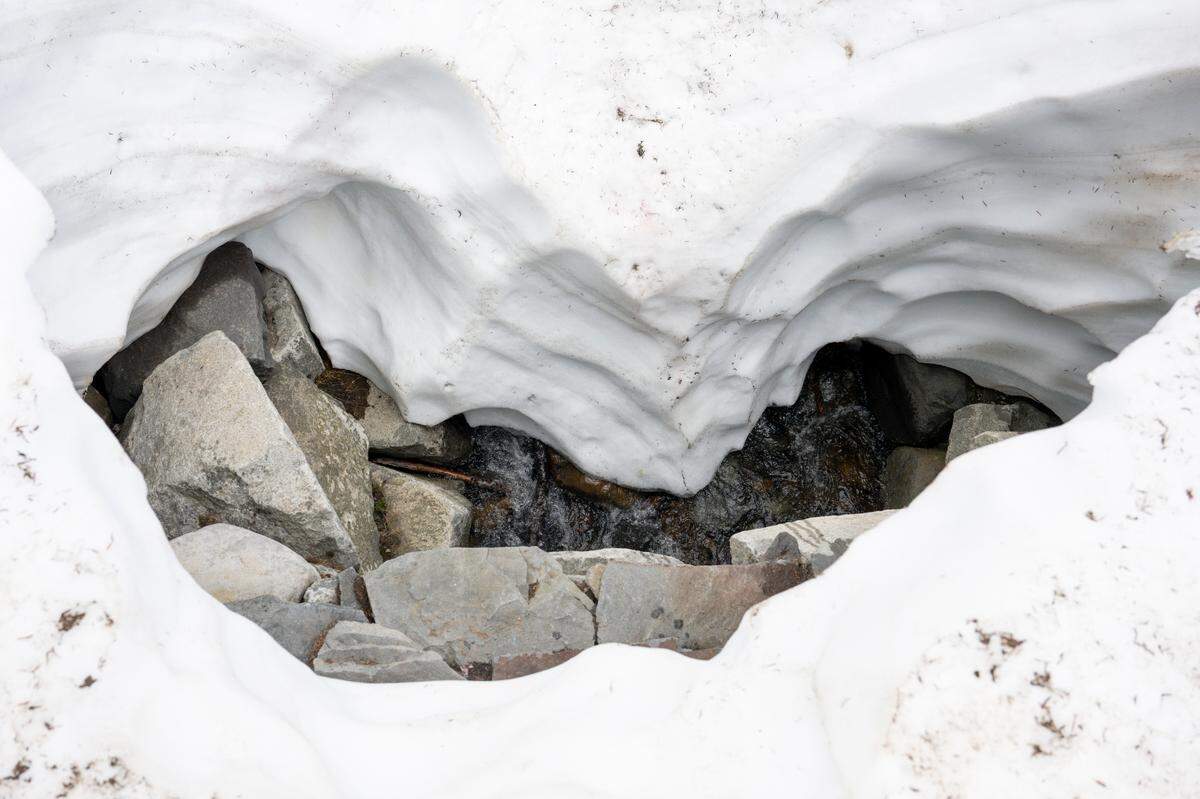 A stream runs underneath several feet of snow as snow melts along the Nisqually Vista Trail on Friday, June 6, 2025, at Mount Rainier National Park.