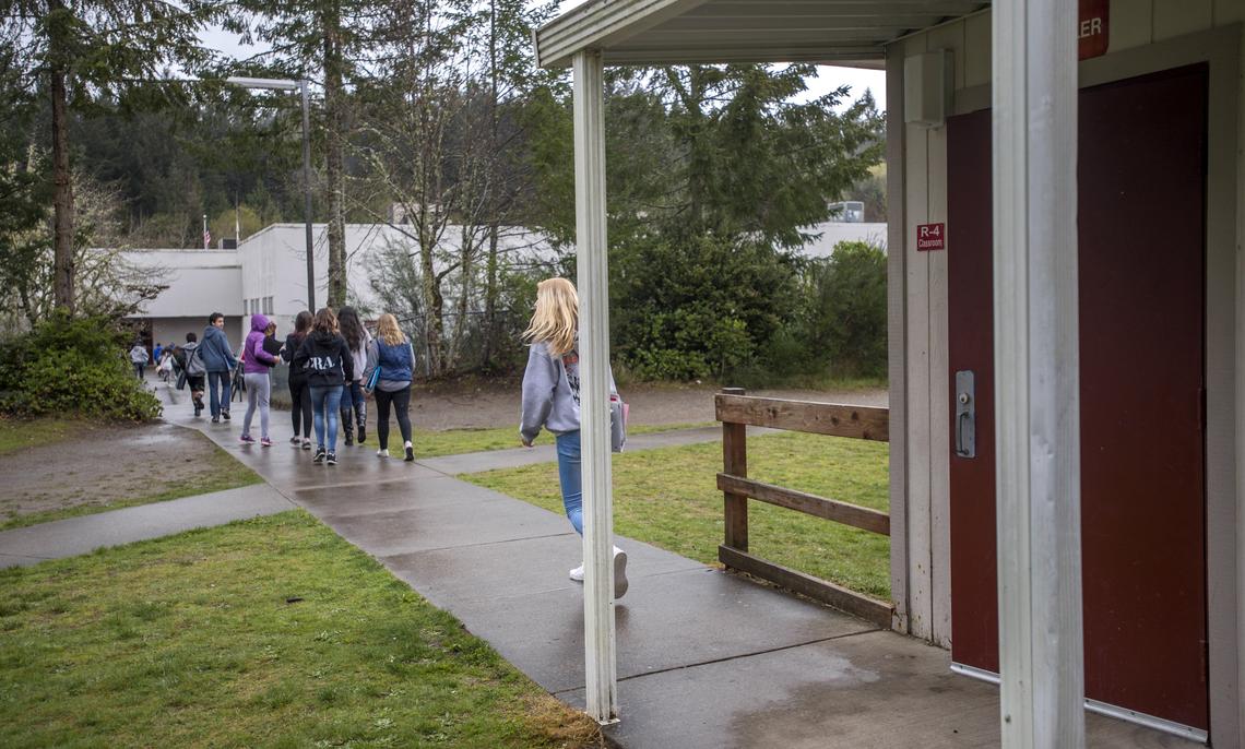 Students head from portable classrooms back to the main building at Key Peninsula Middle School, April 12, 2018.  The district would like to have fewer classes in the portables, partly because having no bathrooms among them and locked doors at the main building wastes students' time.