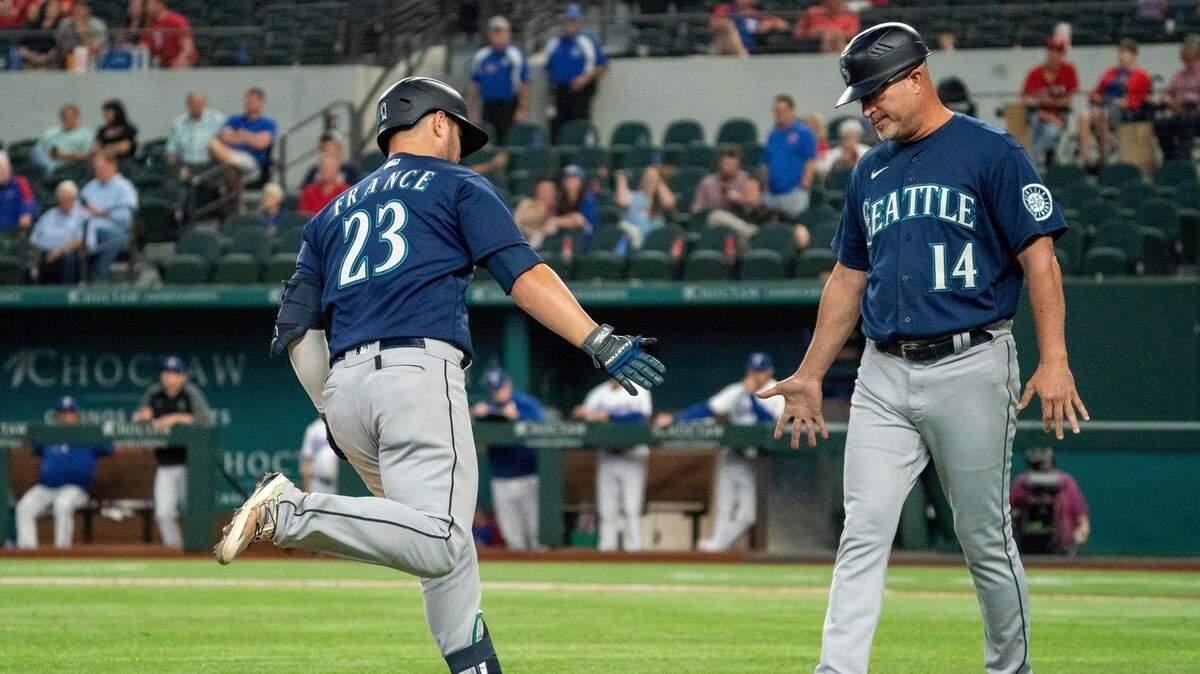 Seattle Mariners’ Ty France (23) is congratulated by third base coach Manny Acta (14) after hitting a two-run home run off Texas Rangers relief pitcher Joe Barlow during the 11th inning of a baseball game Thursday, Aug. 19, 2021, in Arlington, Texas. Seattle won 9-8. (AP Photo/Jeffrey McWhorter)