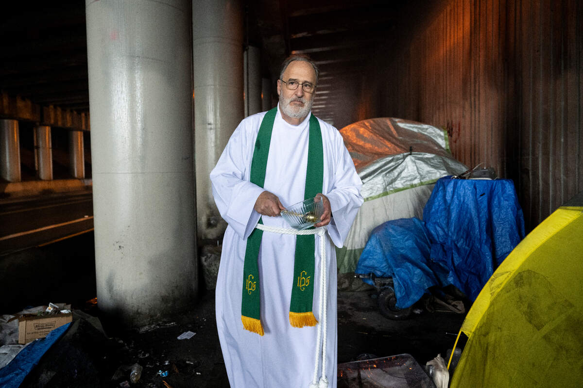 Pastor Ed Jacobs sprinkles Holy Water at the homeless encampment where Robert Grace was murdered near East 28th Street and Bay Street, on Wednesday, Jan. 17, 2024, in Tacoma, Washington.