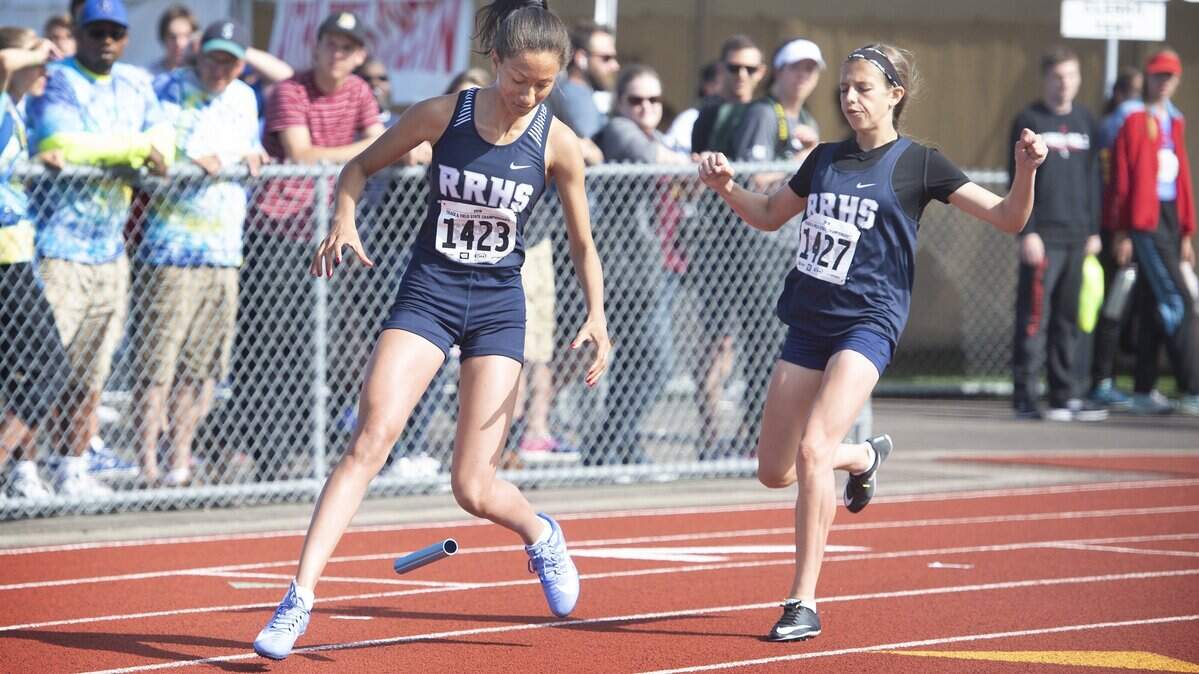 River Ridge’s Ashland Dunaway (1423) and teammate Taylor Woodworth bobble the baton in the 2A girls 4 X 200-meter relay preliminary heat race on the opening day of the state track meet at Mt. Tahoma High School in Tacoma on Thursday, May 24, 2018.