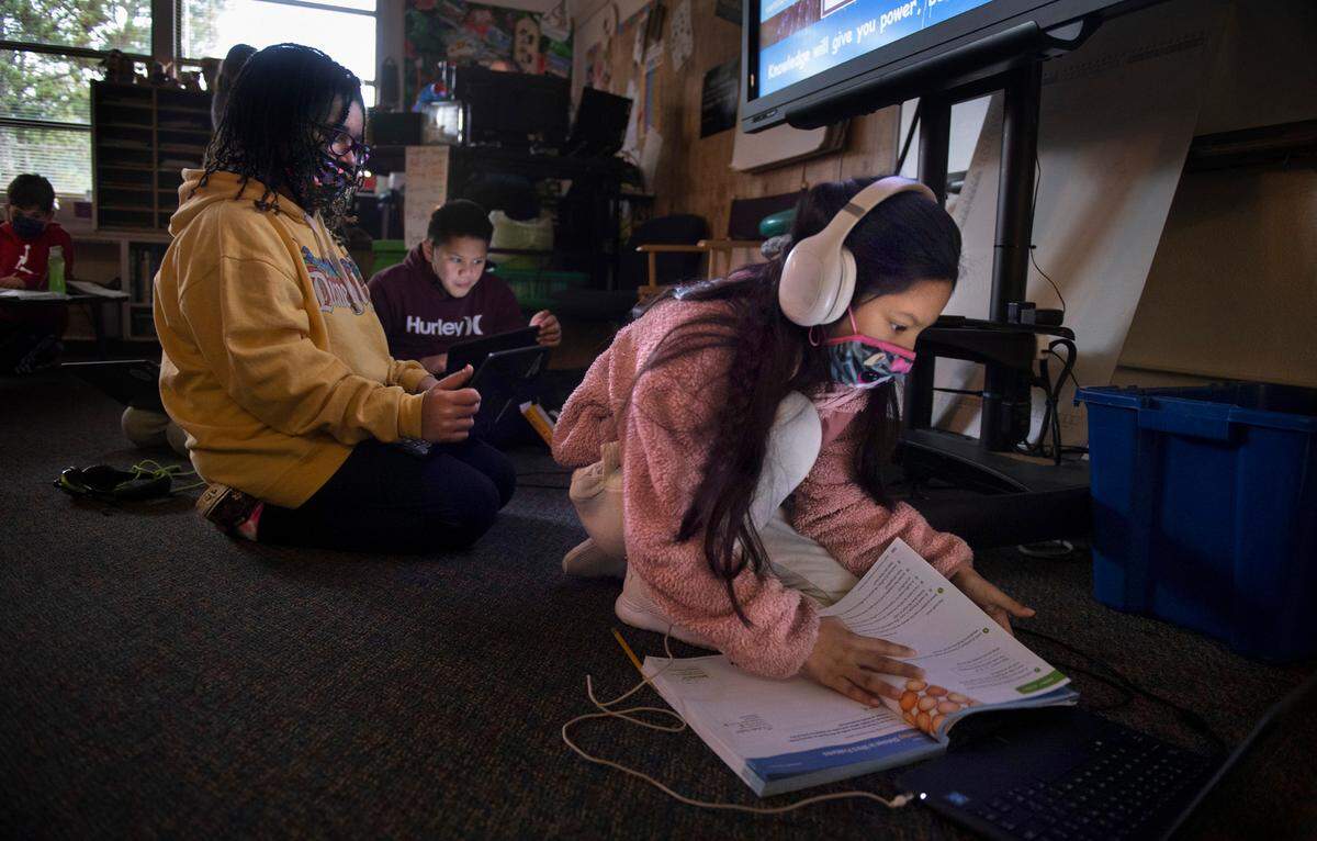 DeLong Elementary students (from left) Allison Turner, Reggie Uluiva and Adalynn Raymundo work on assignments on their district-provided laptop computers in Jennifer Fagan’s combined fourth- and fifth-grade class at DeLong Elementary School in Tacoma, Washington, on Wednesday, Jan. 19, 2022.