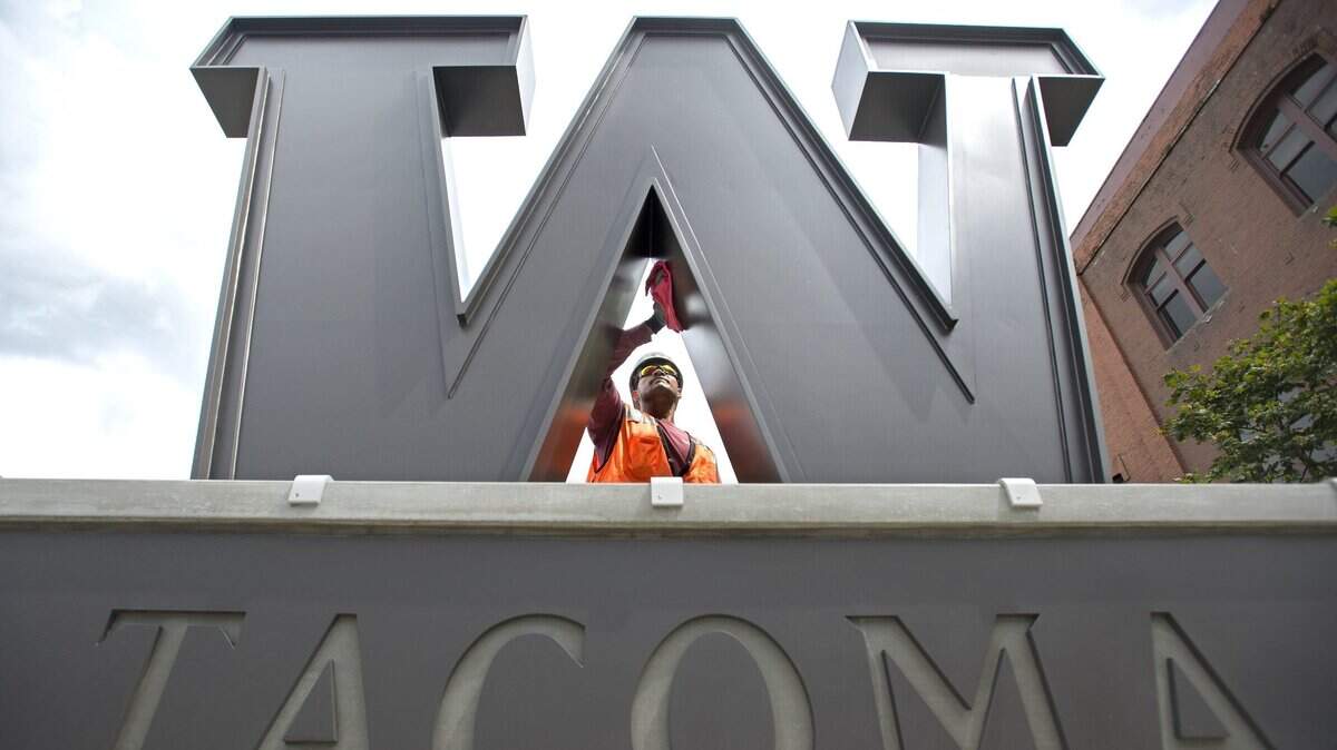 Calvin Fatagi with Marine Vacuum Service cleans the University of Washington Tacoma emblem on the corner of South 19th Street and Jefferson Avenue.