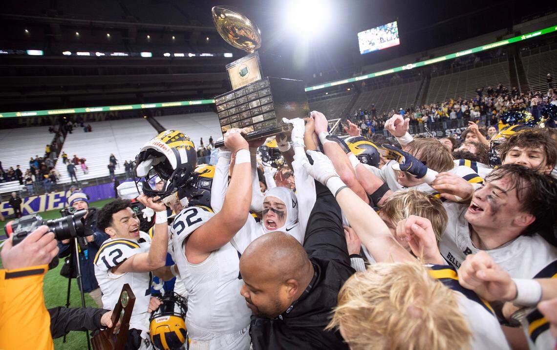 Bellevue’s Bryce Smith (12), Willie Wascher (52) and JJ Pendergast hoist the state championship trophy following the Wolverines’ 14-0 victory over the Yelm Tornados in Friday night’s 3A football state championship game at the University of Washington Stadium in Seattle, Washington, on Dec. 1, 2023.