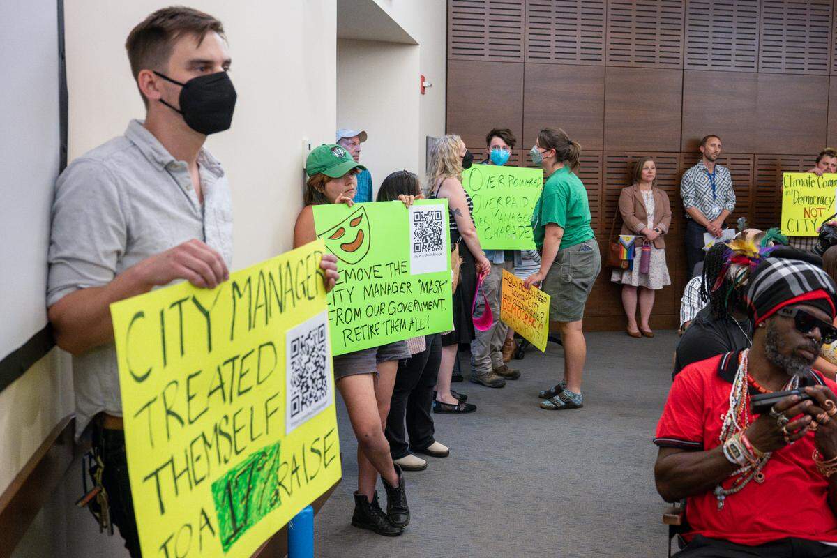 Protesters with the Climate Alliance of the South Sound hold posters up calling for the elimination of the position of city manager during a Tacoma City Council meeting on Tuesday, July 1, 2025, in Tacoma.