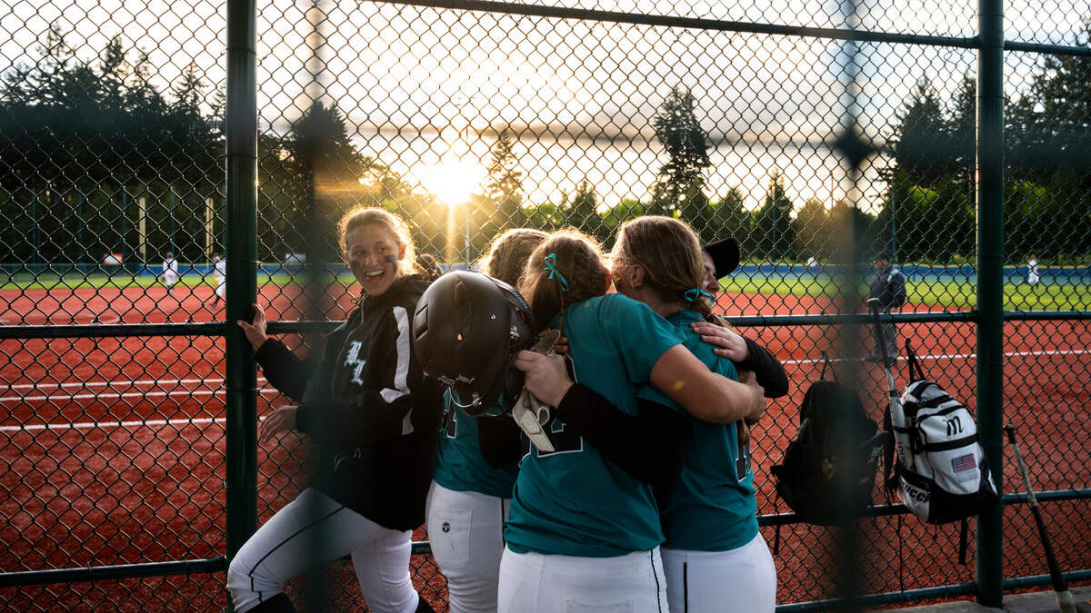 Bonney Lake’s Hallie Beers, 12, is hugged by her teammates in the dugout during the 3A state softball tournament quarterfinals at the Regional Athletic Complex on Friday, May 27, 2022 in Lacey, Wash. Bonney Lake defeated Peninsula 3-2 with a triple play in the seventh inning to win the quarterfinal game.