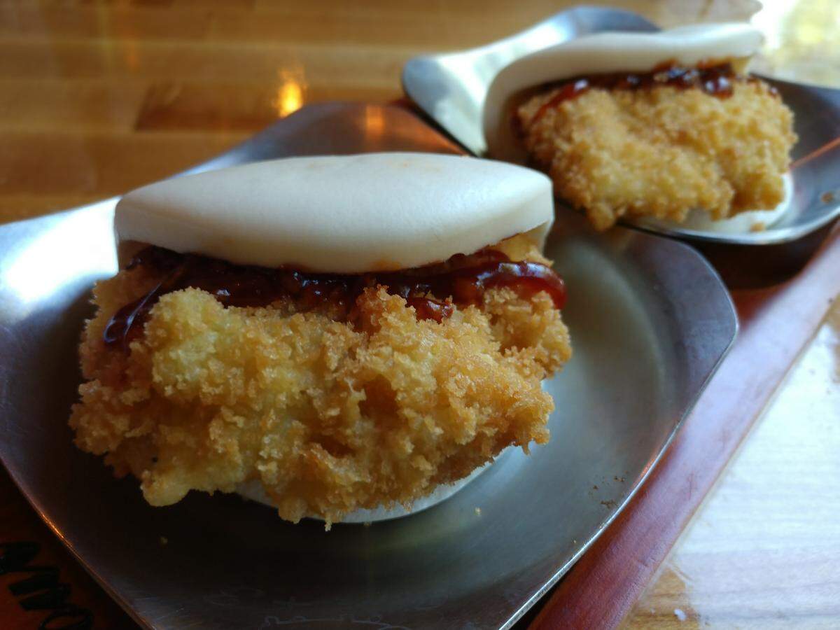 A chicken cutlet is breaded and fried and tucked into split open bao buns at Zen Ramen & Sushi Burrito.