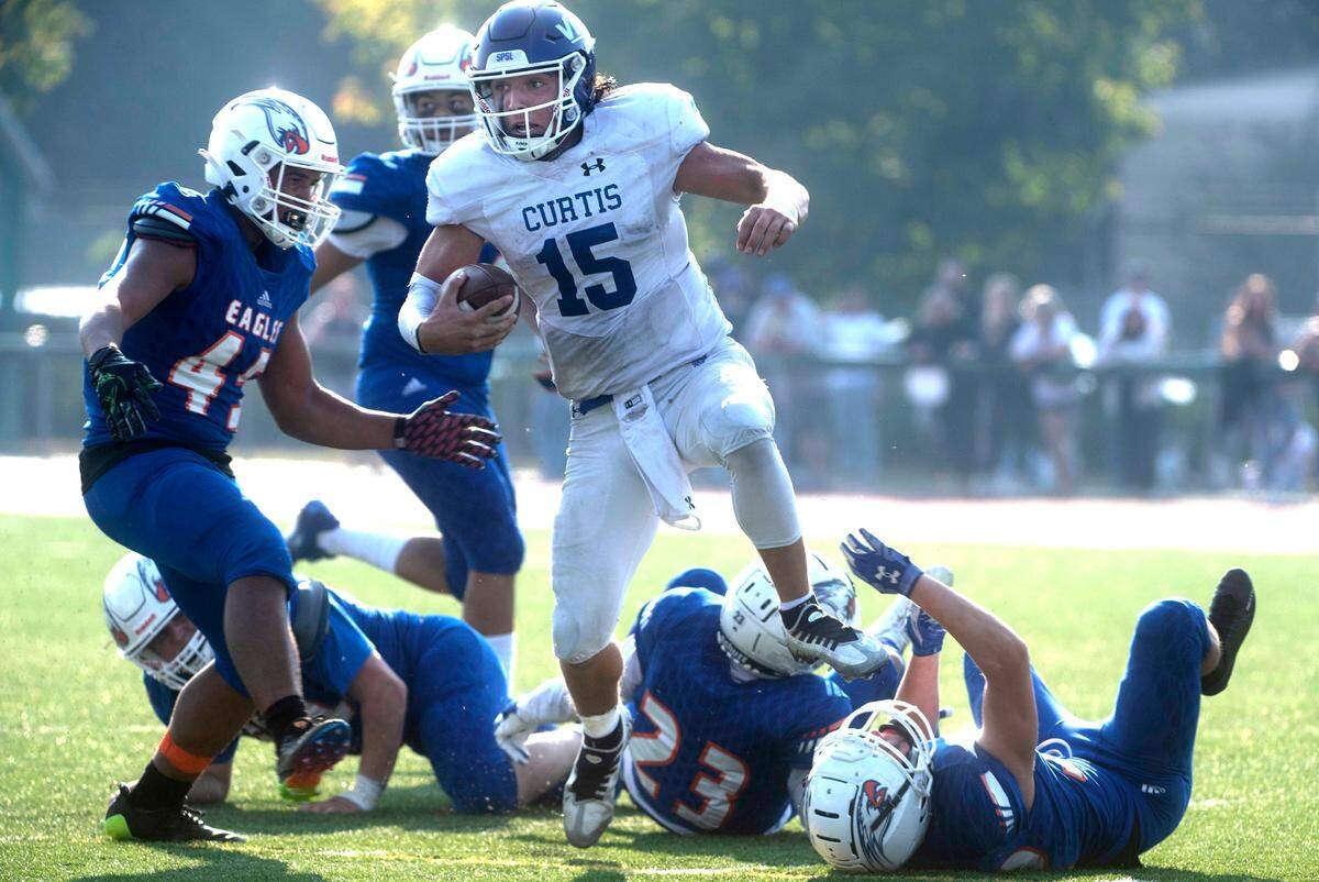 Curtis quarterback Rocco Koch scampers through a bevy of Graham-Kapowsin defenders during Saturday’s football game at Art Crate Field in Spanaway, Washington, Oct. 8, 2022. Graham-Kapowsin won the game, 24-19.