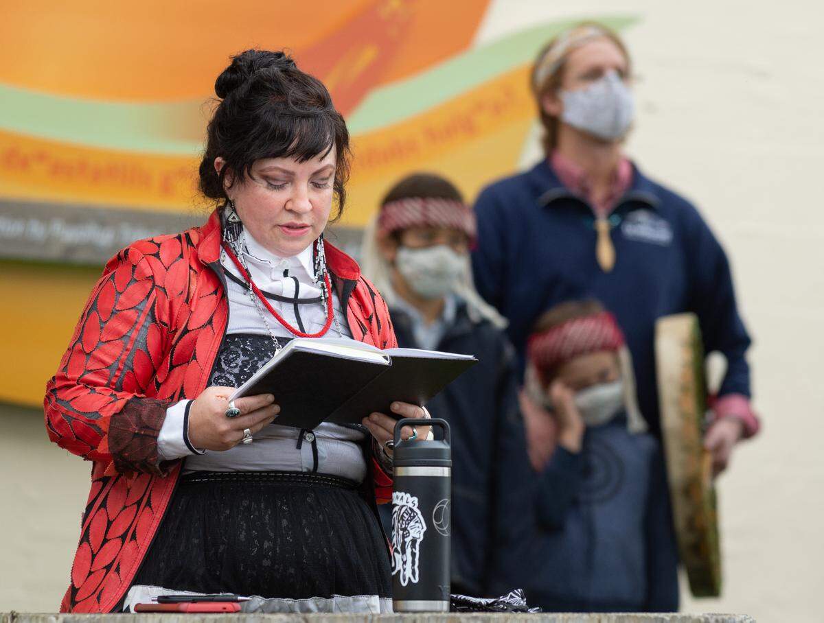Lisa Fruichantie, a citizen of the Seminole Nation of Oklahoma, reads a statement acknowledging the traditional lands of the Puyallup Indian Tribe on Sept. 29, 2021. Paige Pettibon’s mural, produced in collaboration with the Tribe’s language department, can be seen behind her.