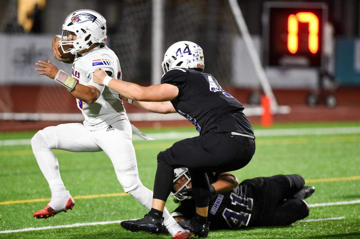 Graham-Kapowsin’s Daveon Superales (15) runs in a touchdown while Sumner’s Cody Cummmings (44) and Dillon Titialii (41) attempt to stop him during the second half of the game at Sumner High School, Thursday, Sept. 28, 2023, in Sumner, Wash.