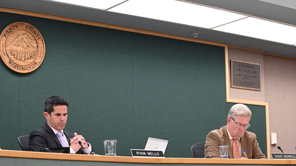 Pierce County Council members Ryan Mello (left) and Dave Morrell listen to senior legislative assistant Mike Kruger during a Pierce County Council meeting, Tuesday, July 25, 2023, in Tacoma.