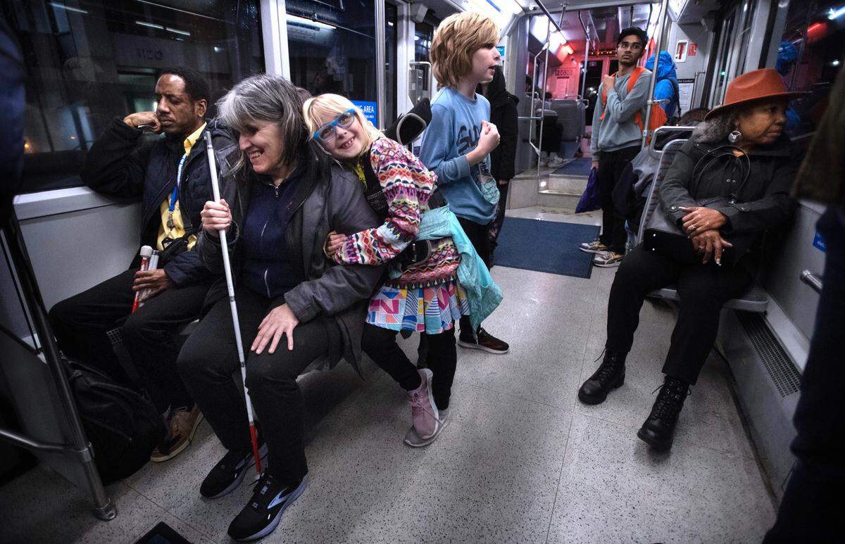 Tacoma Area Commision on Disabilities chair Amin “Tony” Hester and commissioner Hayley Edick - with her children Emily, 7, and Matthew, 10 - ride on the Tacoma Light Rail T-Line through Tacoma, Washington, on Thursday, Nov. 9, 2023.