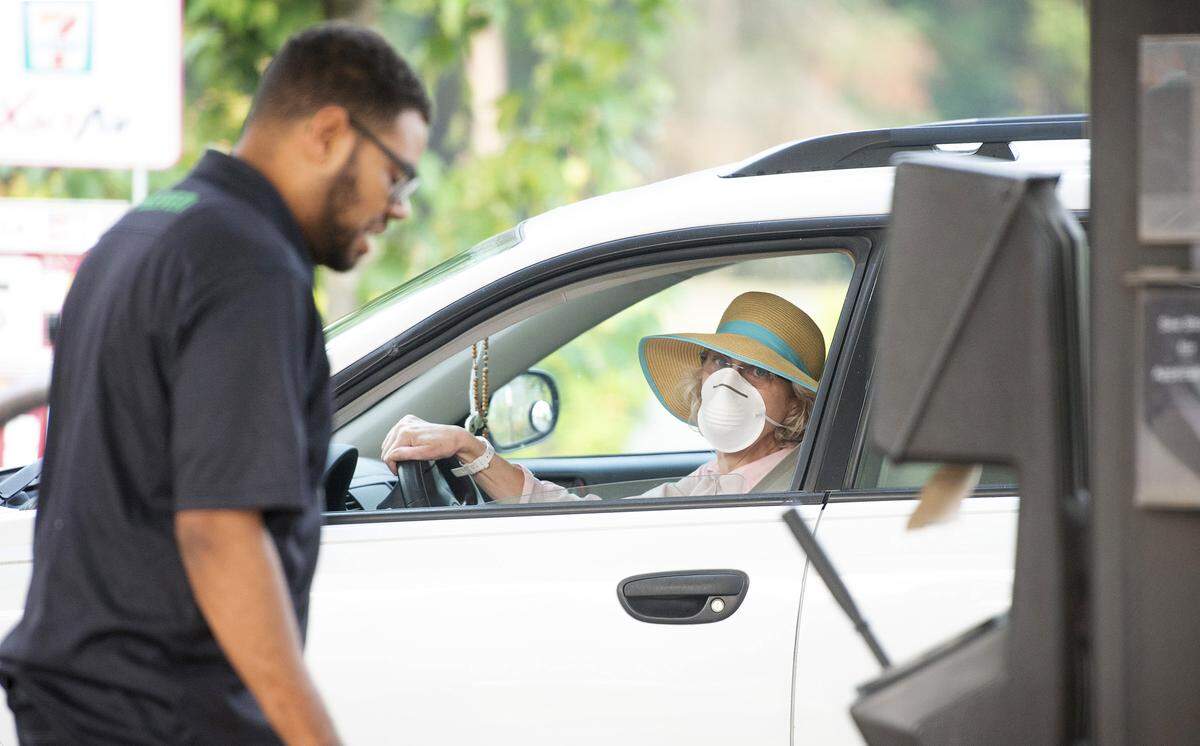A driver masked for the thick, smoky air talks with an employee at a 7-Eleven gas pump in Olympia on Tuesday, Aug. 21, 2018, where dangerous air quality has schools canceling outdoor activities and authorities advising even healthy adults to stay indoors.
